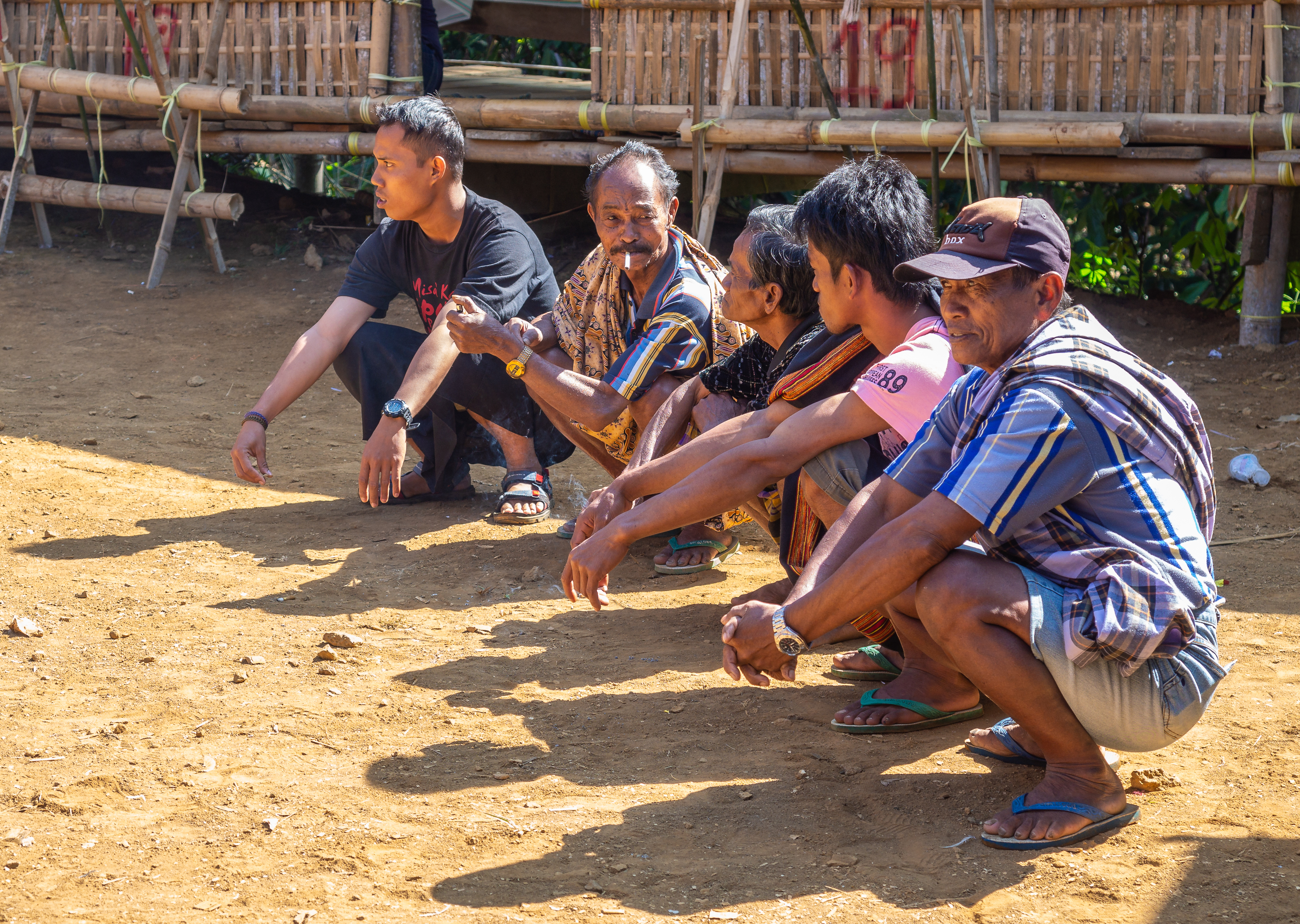 Sulawesi Island, Indonesia - August, 15 2015: Men sitting on haunches and talking in village