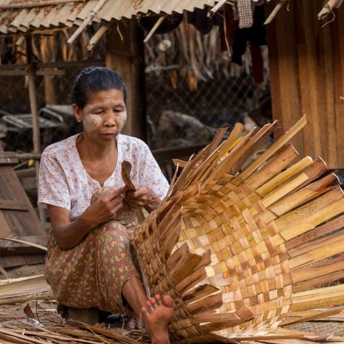Burmese woman is sorting bamboo to make bamboo wall within village nearly Ubein Bridge,