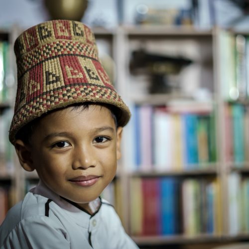 Smiling Asian boy wearing traditional skullcap of Aceh, Indonesia